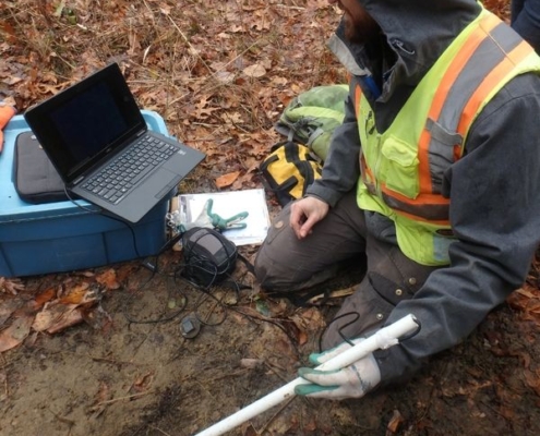 Biologist Jonathan Choquette using a borescope camera and laptop to monitor gartersnakes hibernating in an artificial hibernaculum.