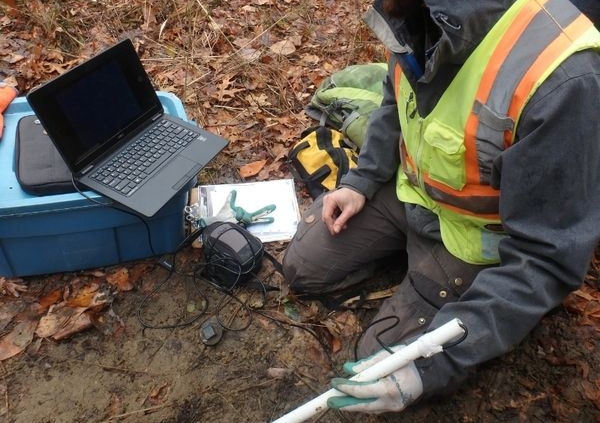 Biologist Jonathan Choquette using a borescope camera and laptop to monitor gartersnakes hibernating in an artificial hibernaculum.